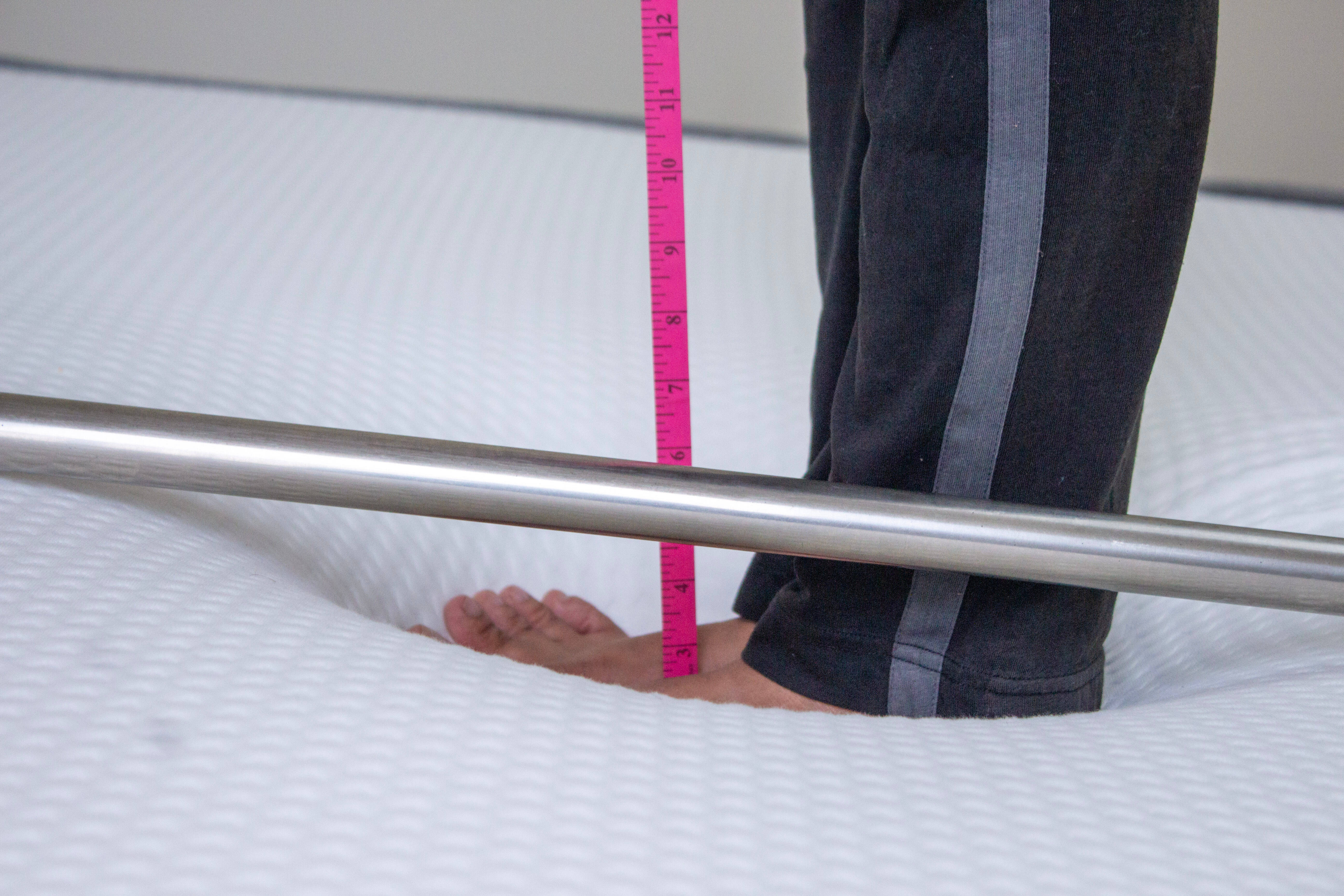 Woman standing on The Sleep Company mattress to determine sinkage.